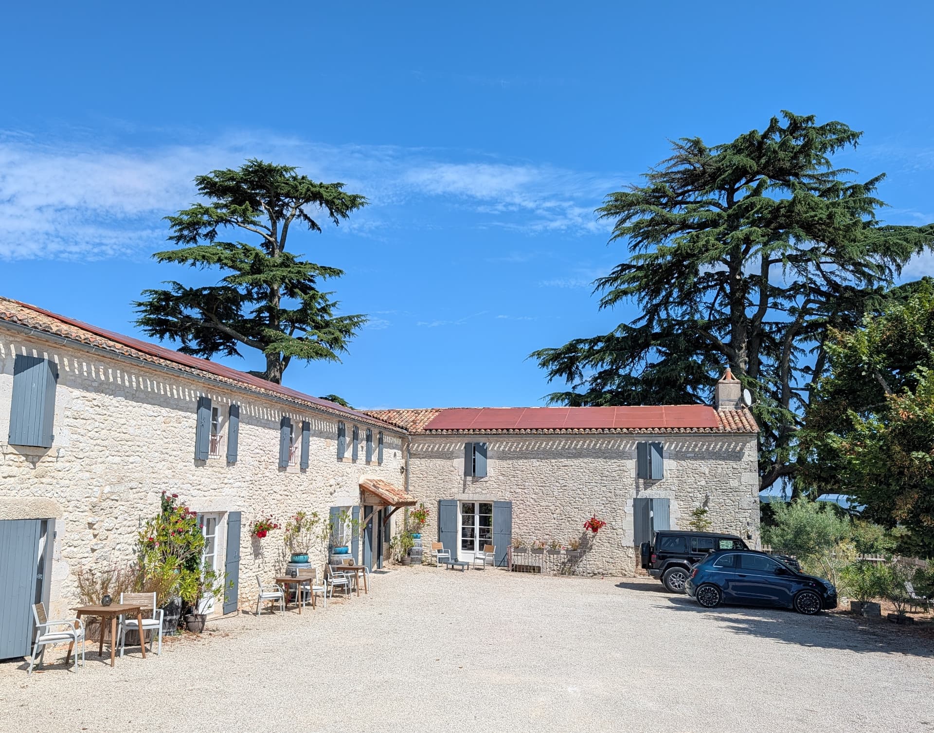The gravel courtyard and stone buildings of The Old Presbytery under a clear blue sky
