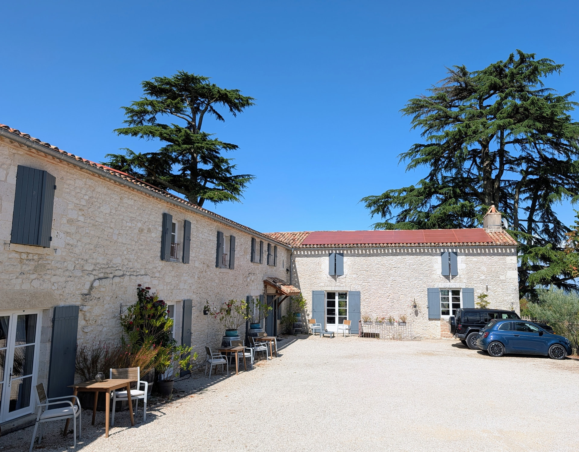 The gravel courtyard and stone buildings of The Old Presbytery under a clear blue sky